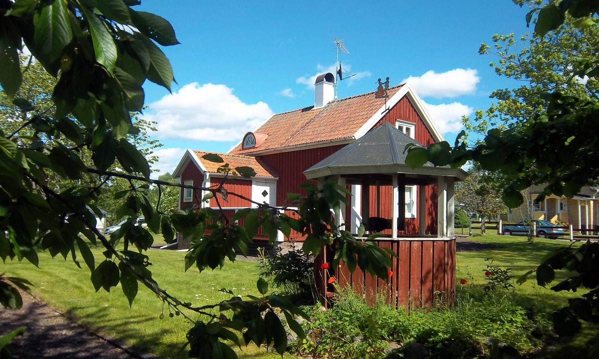 Klavrestrom Hotel | Red wooden house near lake and golf course with boat