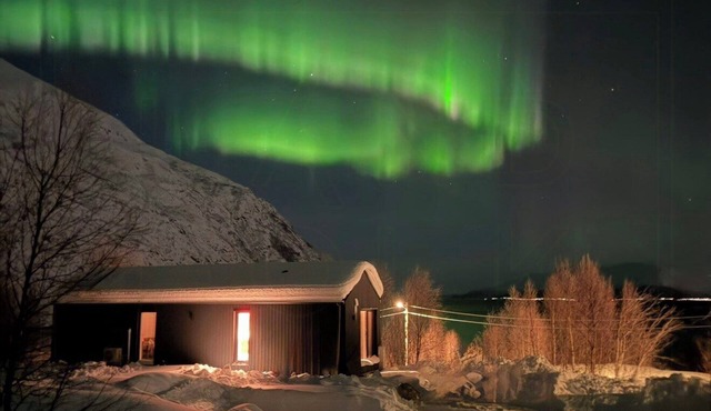 Northern lights cabin in Lyngen Alps by fjord
